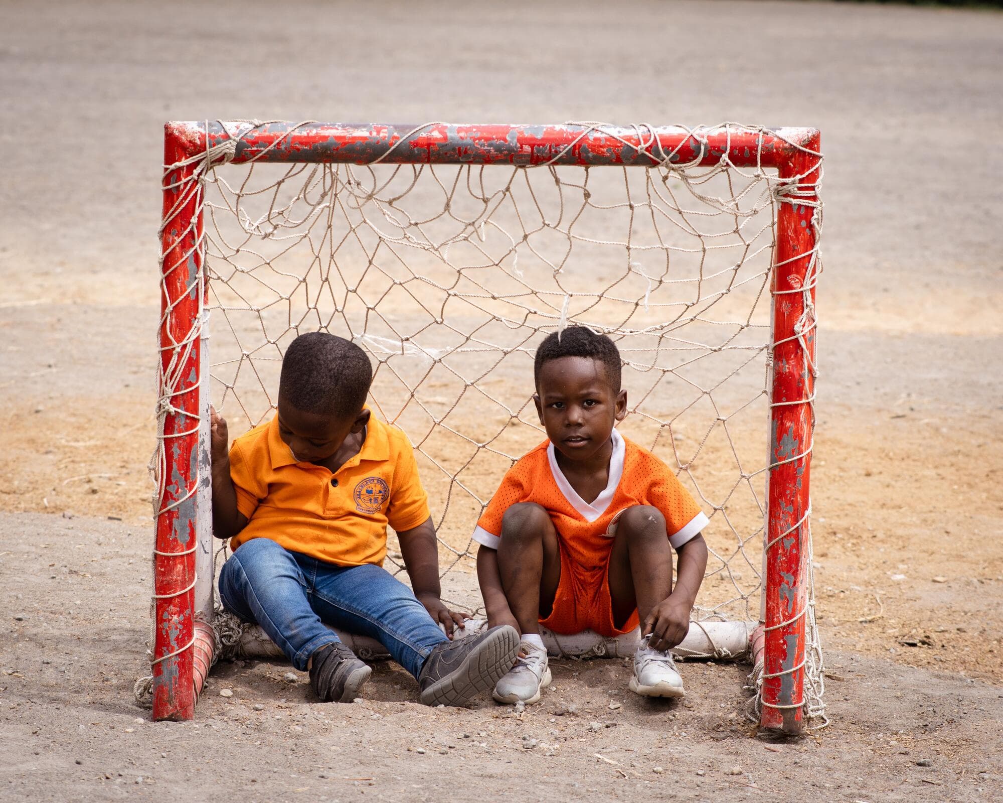 Two Graceland pupils sitting together inside a small goal frame on the school's outdoor sports court